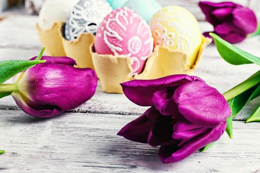 Painted eggs for the Easter holiday and the fresh bud of a tulip