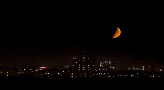 big bloody moon near the horizon in the city