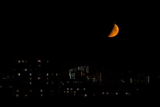 big bloody moon near the horizon in the city