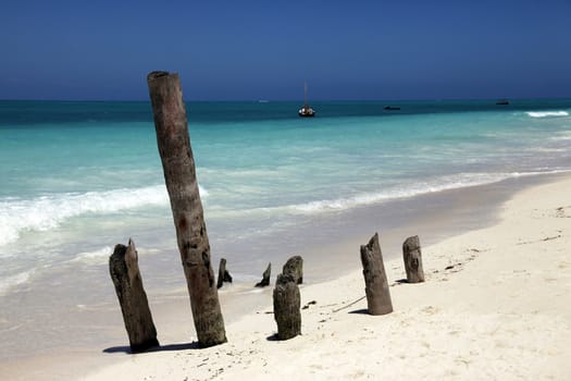 Exoric sail boat in the sea beside the beach with clear blue sky and white sand