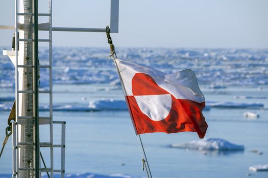 Flags of Greenland flying from the mast of a tourist icebreaker