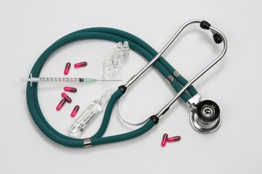 A doctors stethoscope with a syringe and drugs