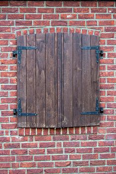 Closed wooden shutter on a brick wall