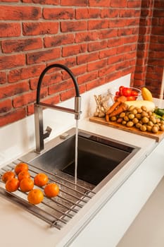 Fragment of modern kitchen with a sink and the mixer and a row the lying vegetables