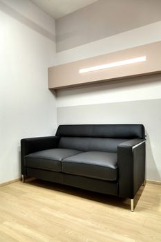 fragment of office room with a black leather sofa in the hall
