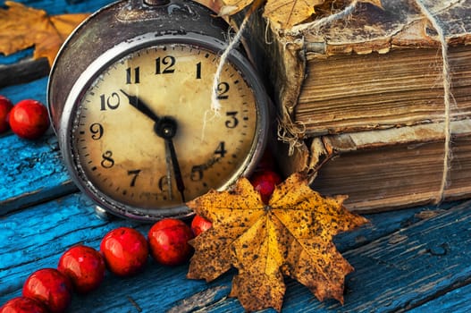 old-fashioned alarm clock and coral beads on a light blue wooden background