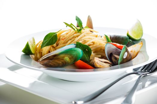 Fresh and spicy seafood pasta in white plate on white background