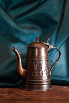 Nice vintage copper tea pot on wood against dark cloth