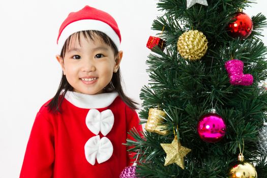 Asian Chinese little girl posing with Christmas Tree on plain white background studio.