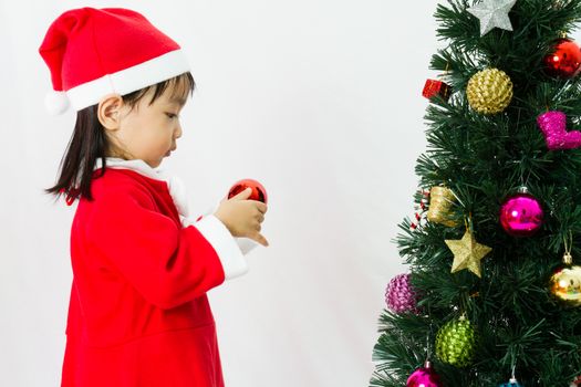 Asian Chinese little girl posing with Christmas Tree on plain white background studio.