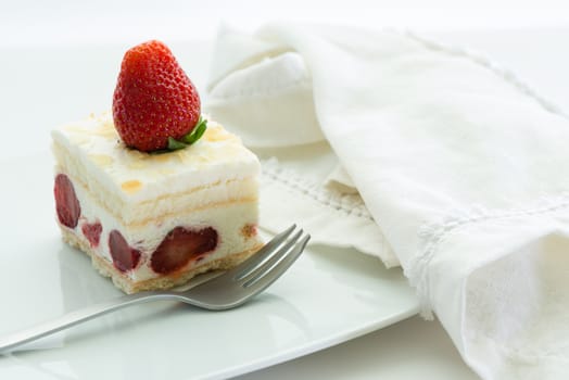Dessert - sweet strawberry cake on white plate and white napkin
