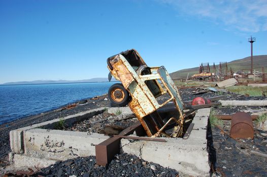 Old broken rusty abandoned car upside down at sea coast, Pevek town, Chukotka, Russia