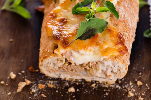 pizza baguette with mozzarella onion and tuna decorated with basil leafs