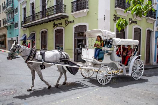 San Juan, Puerto Rico- June 16, 2013: A couple of tourists or locals are enjoying a unique old fashioned horse and buggy ride in historic Old San Juan, Puerto Rico.