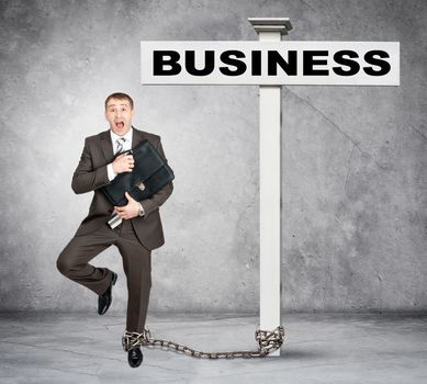 Scared businessman word business on post sign with chain