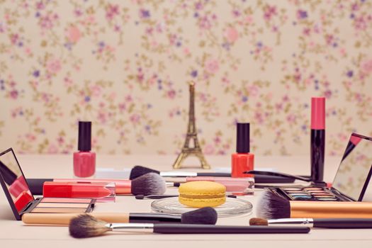 Still life, fashion woman essentials cosmetics. Beauty makeup accessories. Macarons french dessert. Lipstick, brushes, eyeshadow, false eyelashes, mascara.Unusual creative set. Vanilla wood background
