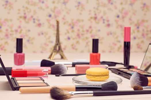 Still life, fashion woman essentials cosmetics. Beauty makeup accessories. Macarons french dessert. Lipstick, brushes, eyeshadow, false eyelashes, mascara.Unusual creative set. Vanilla wood background