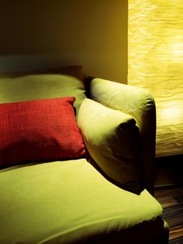 Detail of living room with cozy floor lamp and green sofa.