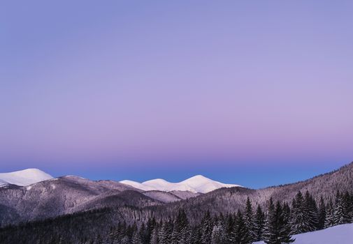 Winter morning view of snowy mountain peaks. Twilight before dawn. Soft light. Lots of clear purple sky. Free space