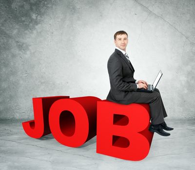 Businessman working on laptop and sitting on word job on grey wall background