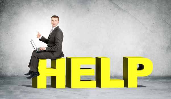 Businessman working on laptop and sitting on word help on grey wall background