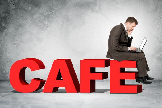 Businessman working on laptop and sitting on word cafe on grey wall background