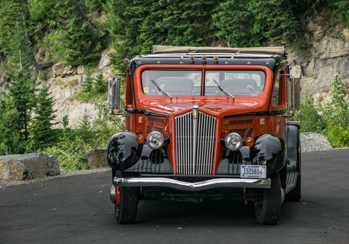 Glacier National Park, Montana, USA-July 11, 2015: The famous Red Bus vehicles of the parks service await passengers to tour Going to the Sun Road inside the park.