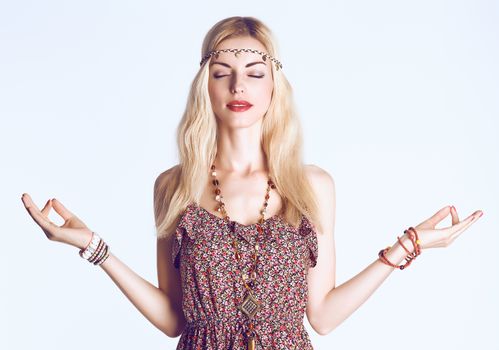 Beauty woman doing yoga with closed eyes. Boho hippie girl meditates, enjoying calm, relax and harmony, ethnic accessories. Positive blonde, long hair in floral sundress. Unusual creative, people