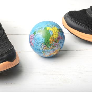 running shoes and earth ball on white wood table concept world healthy