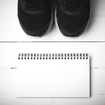 running shoes and notepad on white wood table black and white tone color style