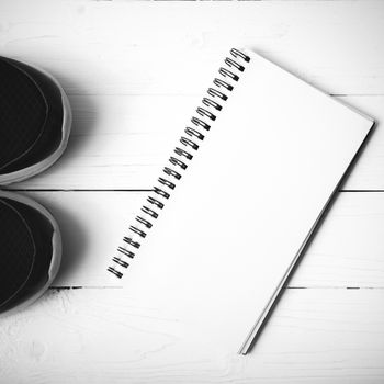 running shoes and notepad on white wood table black and white tone color style