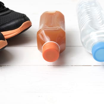 running shoes,drinking water and orange juice on white wood table