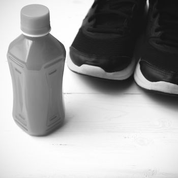 running shoes and orange juice on white wood table black and white tone color style