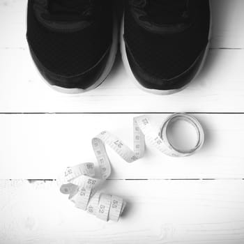 running shoes and measuring tape on white wood table black and white tone color style