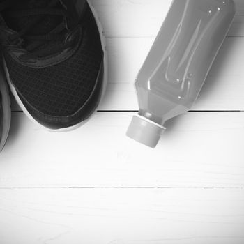 running shoes and orange juice on white wood table black and white tone color style