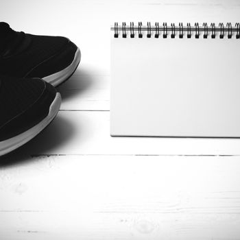 running shoes and notepad on white wood table black and white tone color style