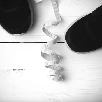 running shoes and measuring tape on white wood table black and white tone color style