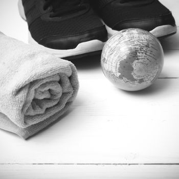 running shoes,towel and earth ball on white wood table concept world healthy black and white tone color style