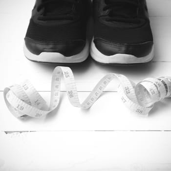 running shoes and measuring tape on white wood table black and white tone color style