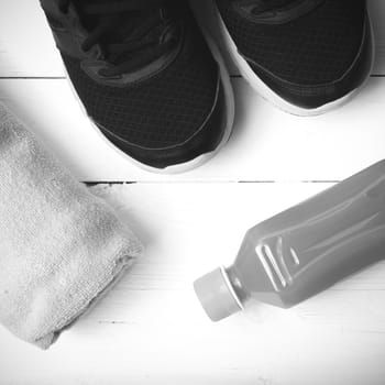 running shoes,towel and orange juice on white wood table black and white tone color style