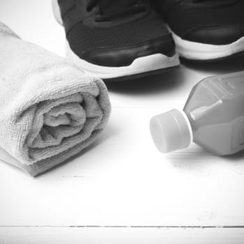 running shoes,towel and orange juice on white wood table black and white tone color style