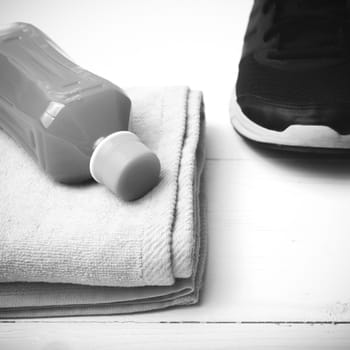 running shoes,towel and orange juice on white wood table black and white tone color style