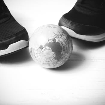 running shoes and earth ball on white wood table concept world healthy black and white tone color style