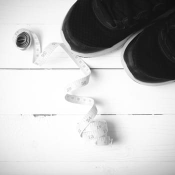 running shoes and measuring tape on white wood table black and white tone color style