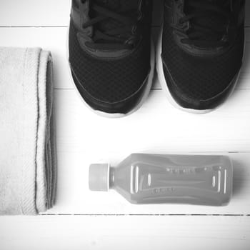 running shoes,towel and orange juice on white wood table black and white tone color style