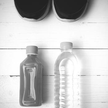 running shoes,drinking water and orange juice on white wood table black and white tone color style