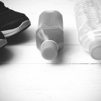 running shoes,drinking water and orange juice on white wood table black and white tone color style