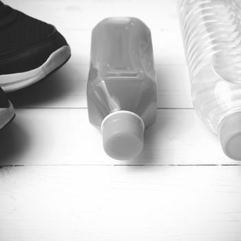 running shoes,drinking water and orange juice on white wood table black and white tone color style