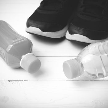 running shoes,drinking water and orange juice on white wood table black and white tone color style