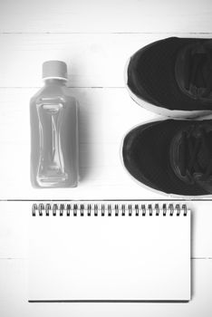 running shoes,orange juice and notepad on white wood background black and white tone color style